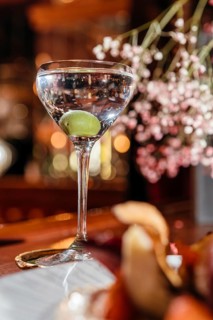 A classic dry martini garnished with an olive, elegantly presented in a crystal glass on a wooden