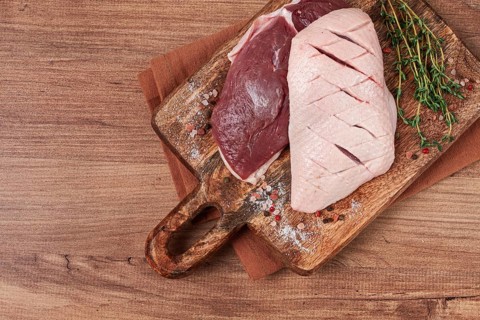 Fresh raw duck breasts, on a wooden chopping board, with herbs and spices, no people