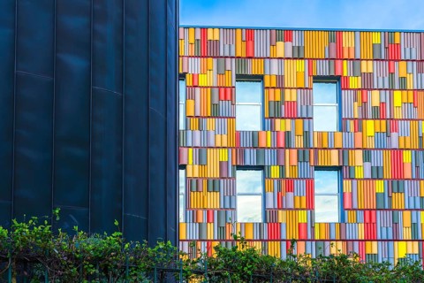 Striking image of a modern building facade featuring a vibrant array of multicolored panels. A