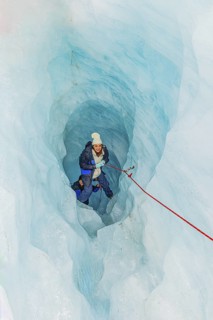 Mountaineer moving up ice cave, Fox Glacier, Westland National Park, South Island, New Zealand