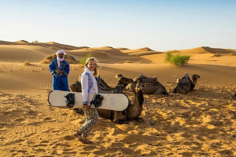 Young woman with snowboard in the sand dunes, near Merzouga, Meknès-Tafilalet region, Erg Chebbi,