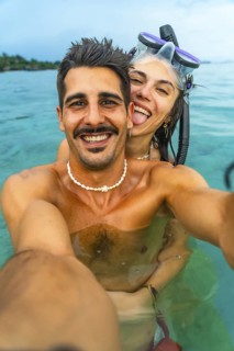 Young couple having fun taking a selfie while snorkeling in the crystal clear turquoise water of a