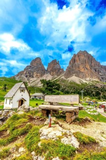 Picturesque landscape showcasing a wooden bench, a small chapel, and the towering peaks of the