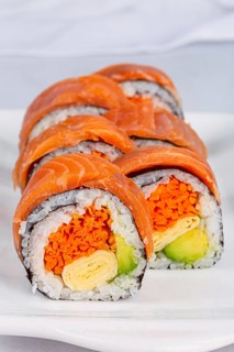 Close up of sushi rolls with fresh salmon, rice, avocado, carrot, and omelet, showcasing vibrant