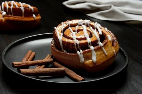 Cinnamon roll on plate and cinnamon sticks