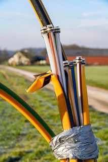 Fibre optic connection, empty conduits protrude from the ground along a dirt track, into which the