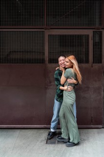 A joyful Colombian lesbian couple sharing an embrace against an urban backdrop, symbolizing love,