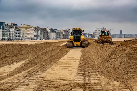 Bulldozers when distributing sand on the beach in the town of Knokke-Heist, part of coastal