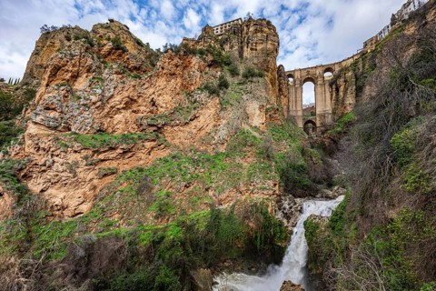 Wide angle view from the bottom of the gorge featuring the massive arches of Puente Nuevo bridge