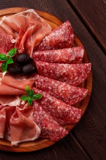 Assortment, sliced meat appetizer, prosciutto, salami and ham, with olives, breakfast, top view,