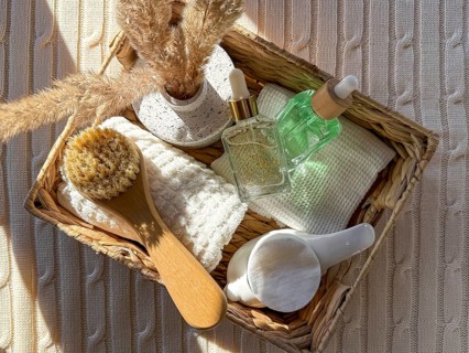 A top view of a woven basket containing spa essentials such as a natural brush, cosmetics, luxury