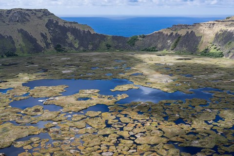 Rano Kau volcano crater lake with floating Totora reed islands, view across the crater rim to the