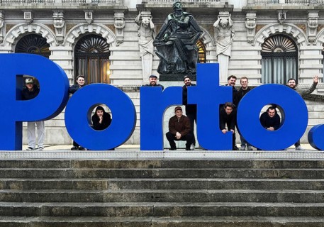 Large, blue postage lettering in front of the town hall with men posing, group photo in front of