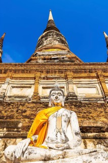 Stone Buddha statue decorated with yellow cloth, historic Buddhist temple complex, Ayutthaya,