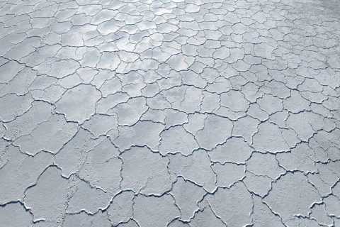 Aerial view of a saline mudflat with a distinctive cracked surface pattern. The image captures the