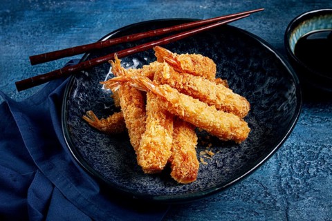 Shrimp in tempura, deep fried, on a black plate, with soy sauce, close-up, top view, no people