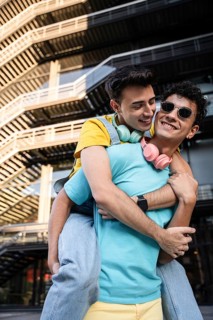 A gay couple enjoys a playful moment outdoors, embodying happiness and connection. They wear