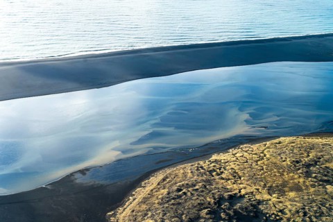 Stunning aerial view of a river delta blending into the sea on the Icelandic coastline, featuring