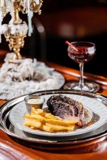 Elegant blue cabbage steak served with crispy fries and creamy sauce on a decorative plate. A