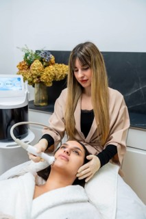 Young woman relaxing while a beautician performs a facial aesthetic treatment using advanced