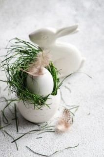 A meticulously styled Easter setting featuring a white egg cradled in vibrant green grass,