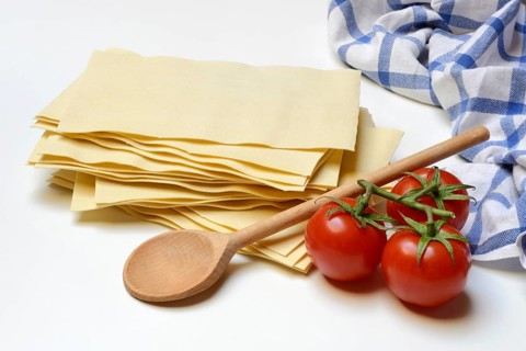 Lasagna, dried lasagna leaves with tomatoes and cooking spoon