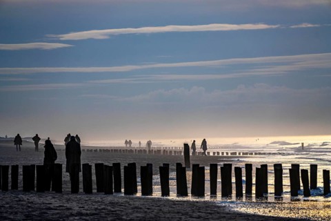 Winter on the North Sea, sunset at sea, beach walkers, coastal protection, through wooden posts,