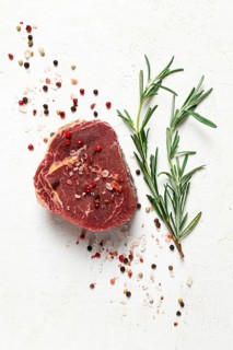 Fresh, raw rib eye steak, with spices, on a white background, top view