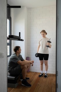 A father and daughter enjoying a home workout session, focusing on weight training. The girl lifts