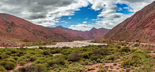 Panoramic view of red mountains and vegetation with clouds, the landscape and colorful rock