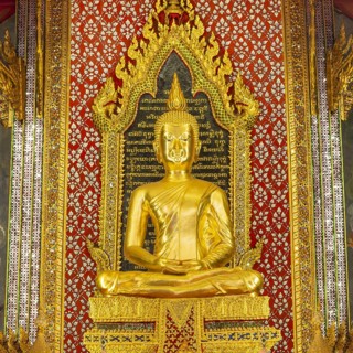 Golden meditating Buddha surrounded by wall paintings with Buddhist teachings and representations