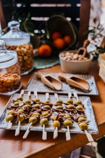 A tray of appetizer skewers with green olives and anchovies is beautifully arranged on a rustic