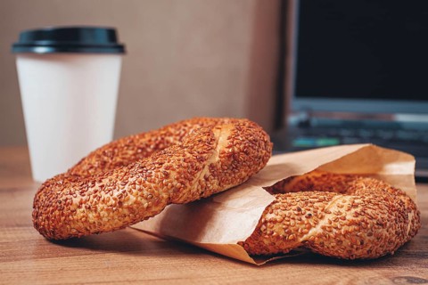 Simits with coffee on a wooden table, with a laptop, in a cozy working environment, snack,