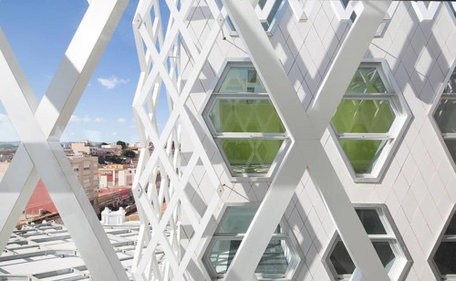 A modern auditorium facade featuring a lattice design with hexagonal windows. The structure
