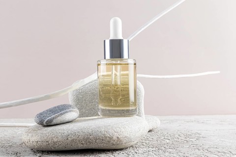 A sleek dropper bottle of skincare rests on smooth stones, evoking a sense of calmness and luxury