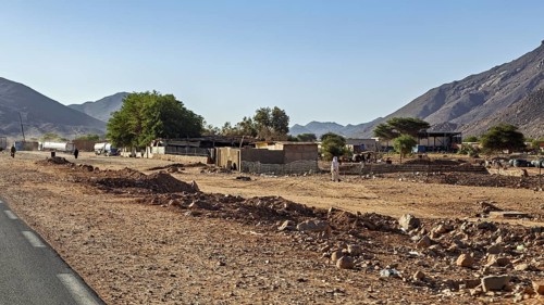 Small village in dry desert landscape with mountains and clear sky, settlement in the Sahara in