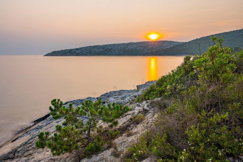 Sunset over crystal clear water on the beach of Ustrine Bay on the island of Cres, long exposure,