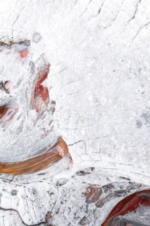 A textured close-up photo of white rocks featuring abstract formations and subtle red accents,