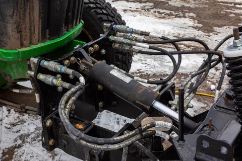 Close-up of black insulated connected hoses, cables and hydraulic lift cyclinder sysyem used to