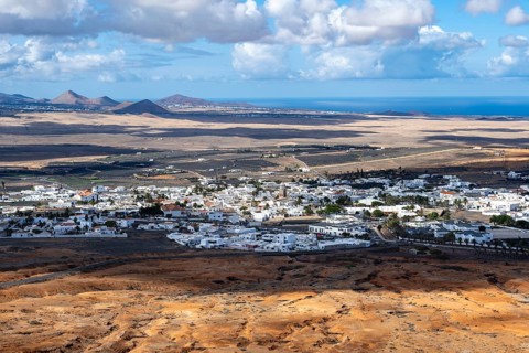 View of town, white houses of Teguise with church tower in dry volcanic landscape, Lanzarote,
