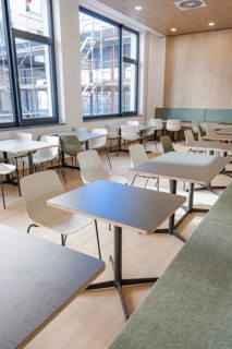 A modern, bright canteen with tables and chairs and large windows reflecting a minimalistic design,