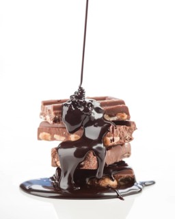 A tantalizing stack of chocolate bars topped with rich, dark chocolate syrup, oozing down and