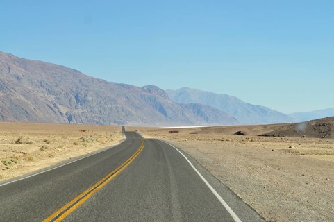 Straight road through dry desert landscape with mountain views, Death Valley National Park, Mojave