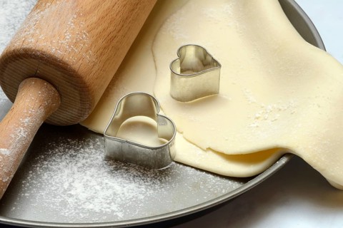 Rolled dough on cake tray with dough rollers and cookie cutters