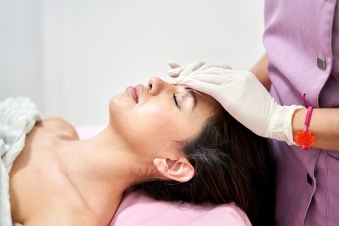 In a serene clinic of aesthetic medicine, a professional applies a facial treatment to a client.