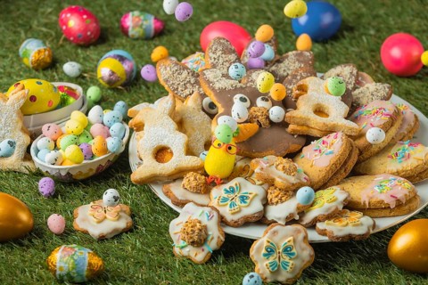 Decorated Easter cookies on a plate with colorful eggs in the grass