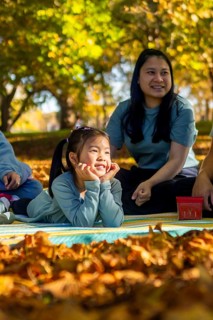 An Asian family enjoys a delightful picnic on a sunny day in a park. Surrounded by vibrant autumn