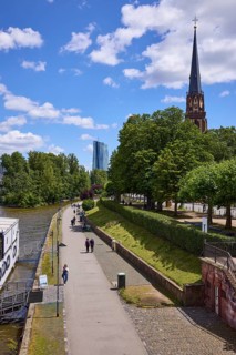 Main river with riverside promenade and Evangelische Dreikönigskirche under blue sky with cumulus