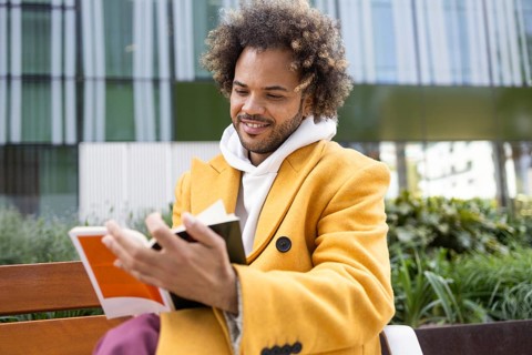 A cheerful Afro man with curly hair, wearing a bright yellow coat, enjoying a peaceful moment