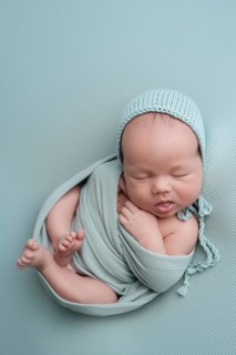 A serene image of a newborn baby peacefully sleeping, wrapped in a soft, pastel blue blanket. The